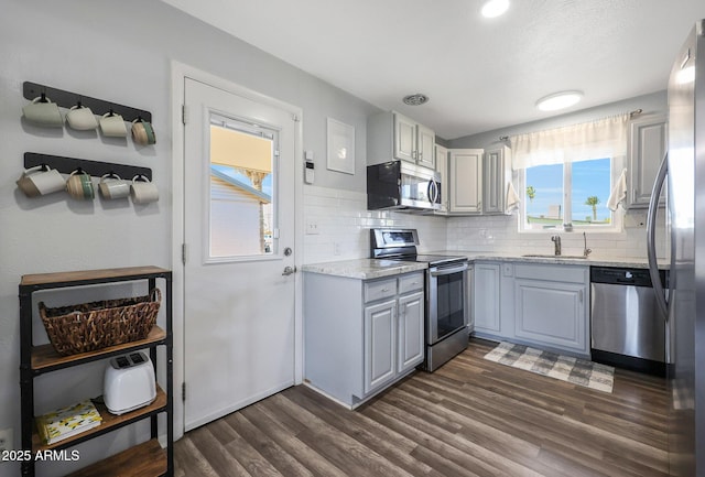 kitchen featuring stainless steel appliances, tasteful backsplash, gray cabinetry, and dark hardwood / wood-style flooring