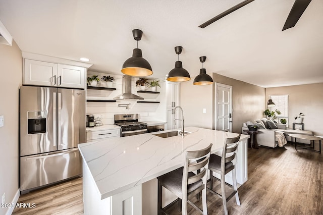 kitchen featuring light stone countertops, sink, extractor fan, white cabinets, and appliances with stainless steel finishes