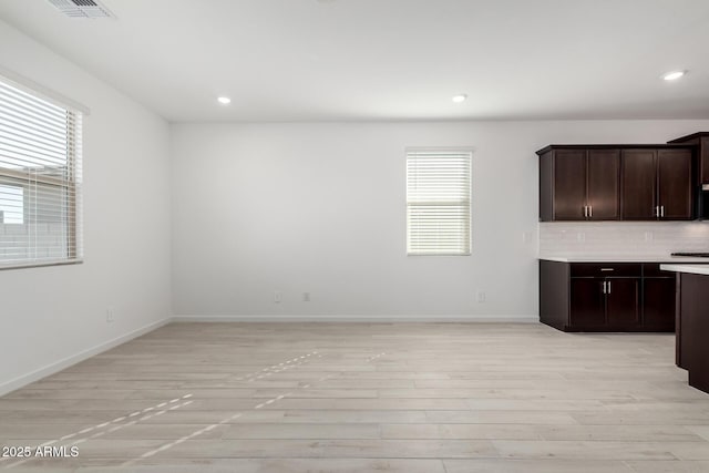 kitchen with light hardwood / wood-style flooring, dark brown cabinets, and backsplash