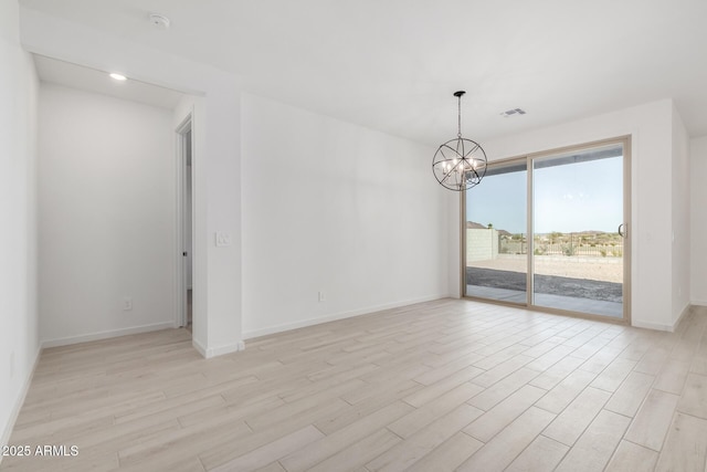 unfurnished room featuring an inviting chandelier and light hardwood / wood-style flooring