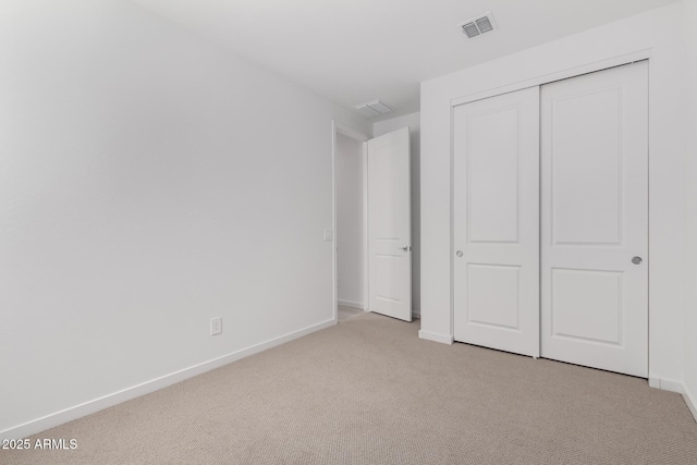 unfurnished bedroom featuring light colored carpet and a closet