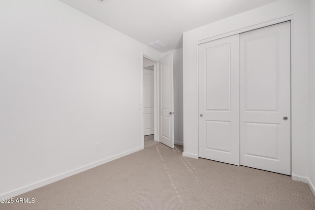 unfurnished bedroom featuring light colored carpet and a closet