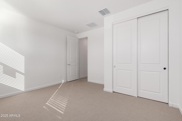 unfurnished bedroom with light colored carpet and a closet