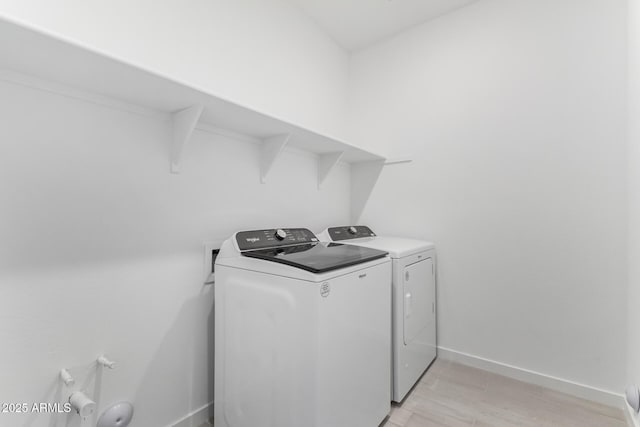 clothes washing area with washer and clothes dryer and light hardwood / wood-style flooring