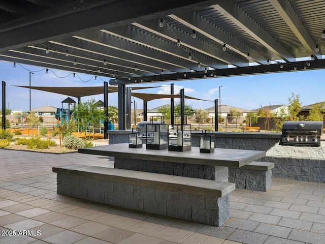 view of patio with exterior bar, a pergola, grilling area, and an outdoor kitchen