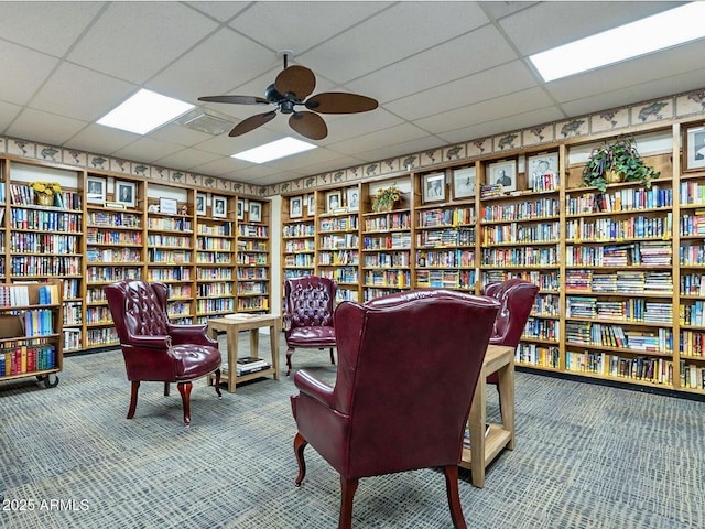 425 S Parkcrest Unit 323, Mesa, AZ 85206 - sitting room with bookshelves, carpet floors, ceiling fan, and a drop ceiling