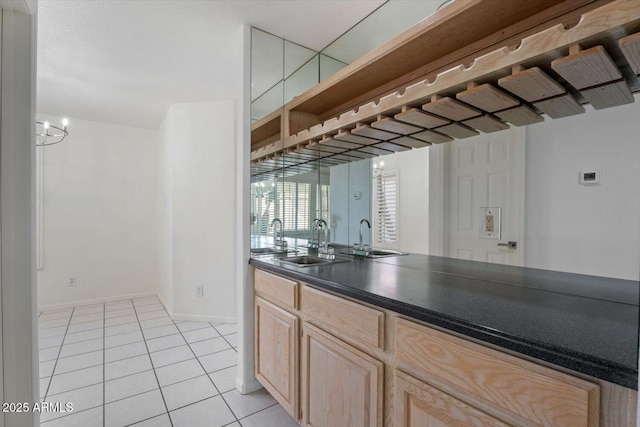 kitchen featuring sink, light tile patterned floors, light brown cabinets, and a notable chandelier