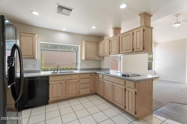 kitchen featuring kitchen peninsula, a wealth of natural light, light colored carpet, sink, and black appliances