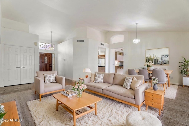 living room with light colored carpet, high vaulted ceiling, and a chandelier