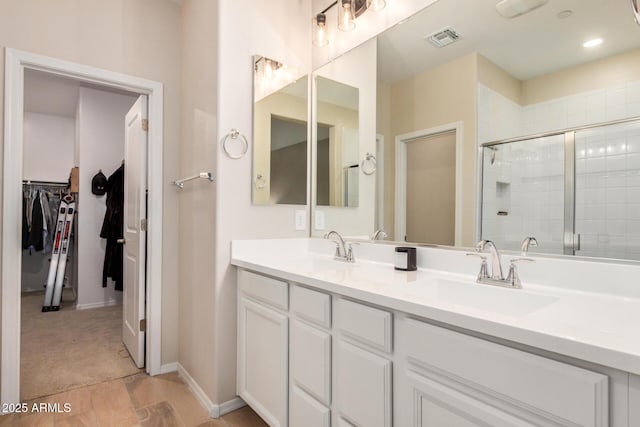 1825 E Hampton Ln Unit 108, Gilbert, AZ 85295 - bathroom with double vanity, a stall shower, a walk in closet, wood finished floors, and baseboards