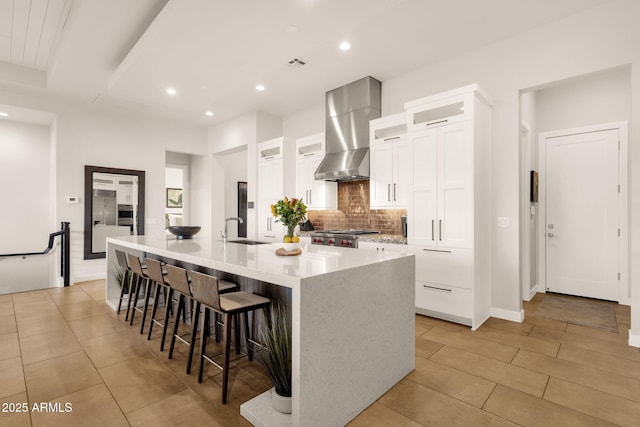 kitchen with a sink, white cabinetry, ventilation hood, a center island with sink, and glass insert cabinets