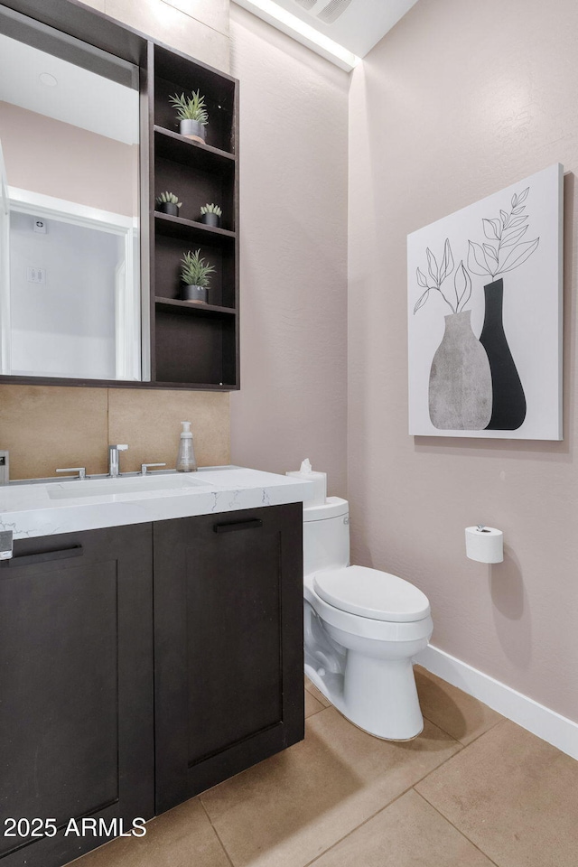 half bath featuring toilet, tile patterned flooring, baseboards, and vanity