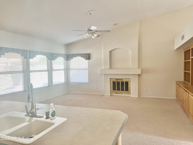 kitchen featuring light brown cabinets, light carpet, sink, vaulted ceiling, and ceiling fan