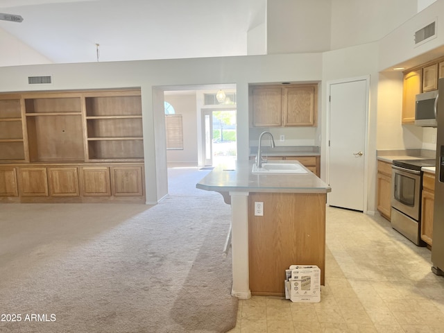 kitchen with sink, light carpet, a breakfast bar, a center island with sink, and appliances with stainless steel finishes