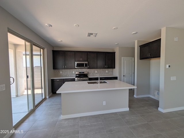 9412 E Sequence Ave, Mesa, AZ 85212 - kitchen featuring appliances with stainless steel finishes, backsplash, light countertops, an island with sink, and light tile patterned flooring
