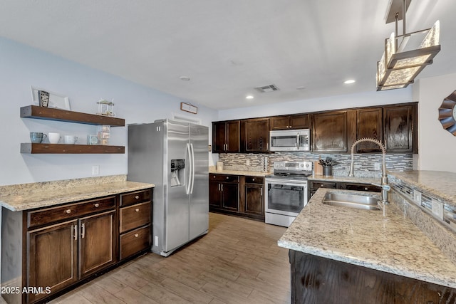 308 E Sheffield Ct, Gilbert, AZ 85296 - kitchen with stainless steel appliances, dark brown cabinetry, light wood-type flooring, tasteful backsplash, and light stone counters