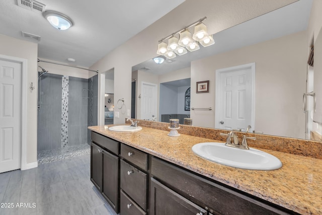 308 E Sheffield Ct, Gilbert, AZ 85296 - bathroom featuring a tile shower, double vanity, and wood finished floors