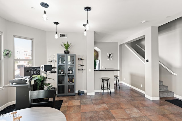 interior space featuring visible vents, baseboards, freestanding refrigerator, and hanging light fixtures