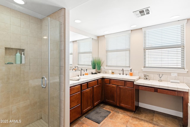 bathroom with double vanity, visible vents, a stall shower, and a sink