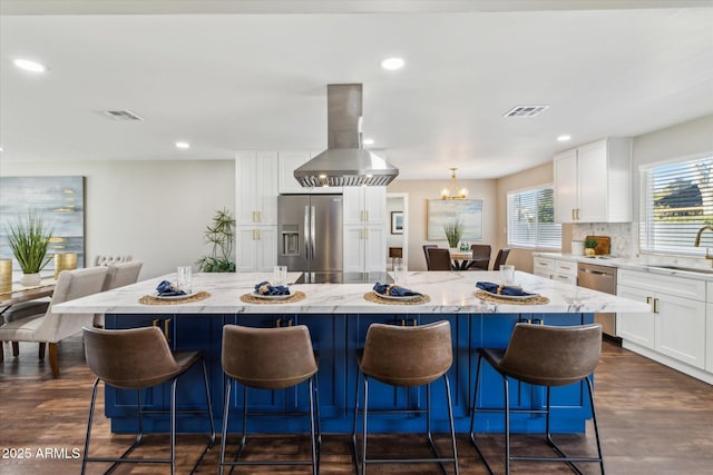 kitchen featuring white cabinets, stainless steel appliances, island exhaust hood, and a kitchen island