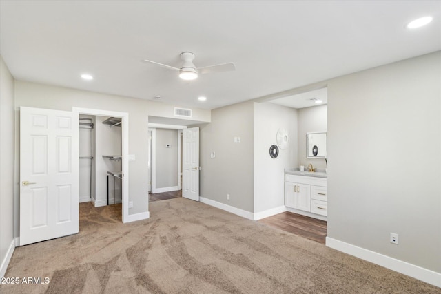 unfurnished bedroom featuring a spacious closet, ensuite bathroom, a closet, carpet flooring, and ceiling fan