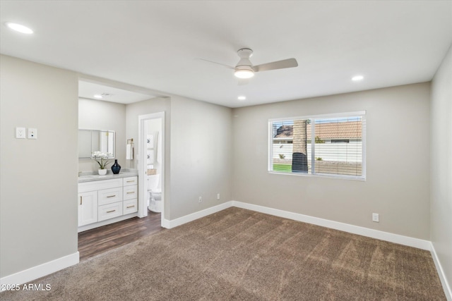 spare room featuring ceiling fan and dark carpet