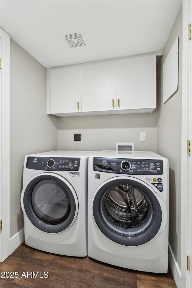 laundry room featuring washing machine and dryer, cabinets, and dark hardwood / wood-style flooring