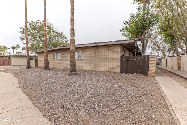 view of side of home featuring fence and brick siding