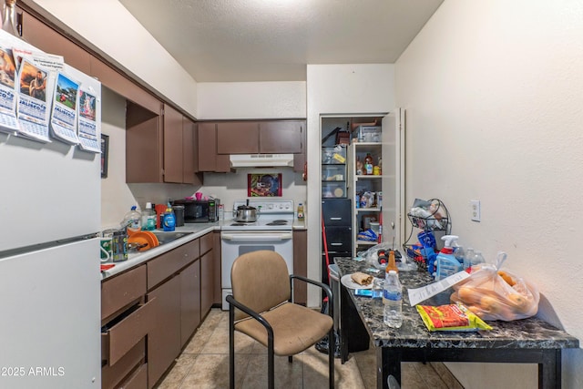 kitchen with light tile patterned floors, under cabinet range hood, white appliances, a sink, and dark brown cabinets