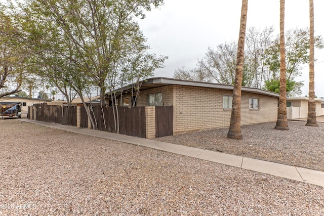 view of side of property with fence and brick siding
