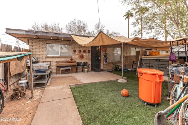 rear view of house featuring a patio area, a yard, and brick siding