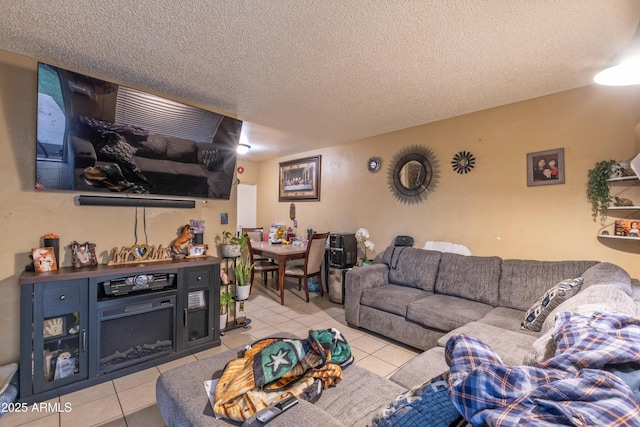 living room with light tile patterned floors, a textured ceiling, and a glass covered fireplace