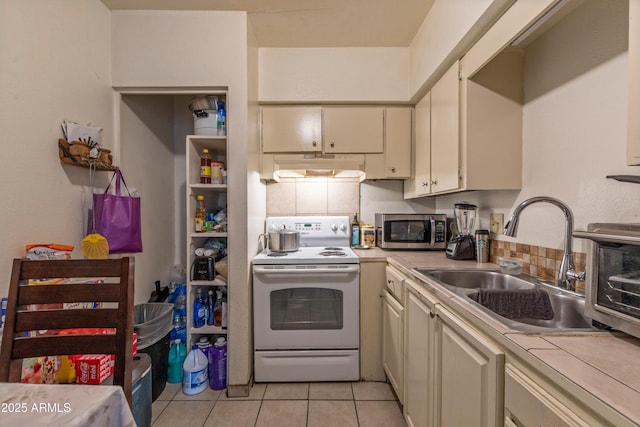 kitchen featuring cream cabinets, white range with electric stovetop, stainless steel microwave, and light countertops