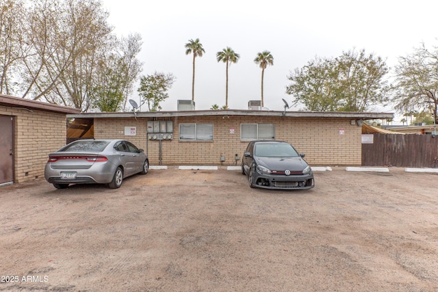 single story home featuring uncovered parking, fence, and brick siding