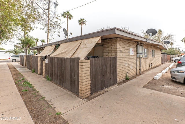 view of property exterior featuring fence and brick siding