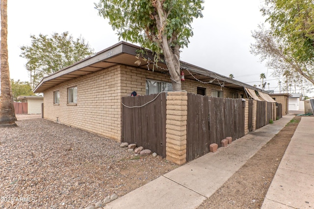 view of side of property with fence and brick siding