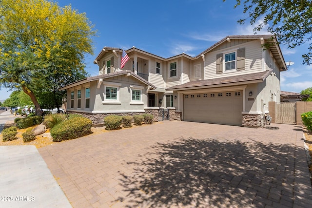 craftsman-style house featuring a garage, fence, stone siding, decorative driveway, and a gate