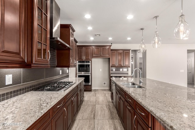 kitchen with wall chimney range hood, light stone countertops, a sink, stainless steel appliances, and decorative backsplash