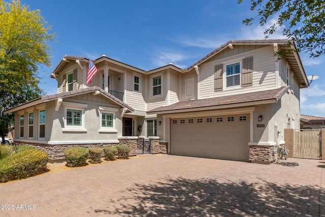craftsman-style house featuring a garage, fence, stone siding, decorative driveway, and a gate