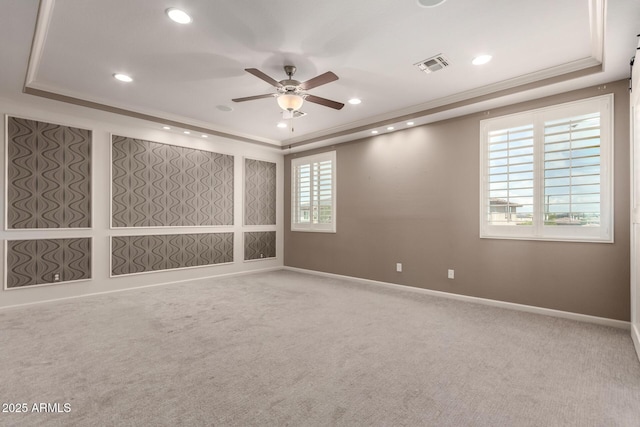 carpeted spare room featuring visible vents, a tray ceiling, and a healthy amount of sunlight