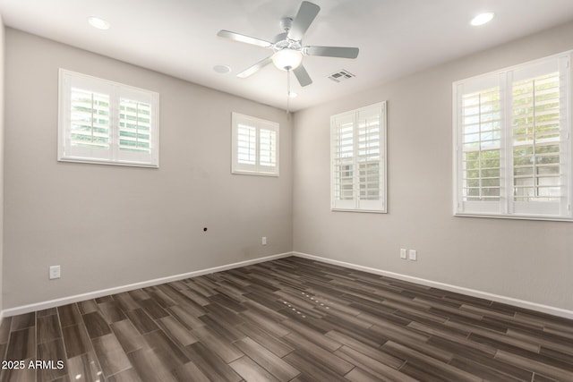 empty room featuring visible vents, baseboards, ceiling fan, and dark wood-style floors