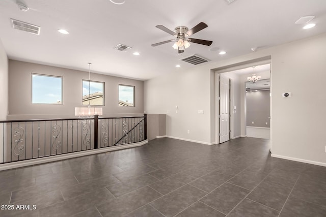 unfurnished room with dark tile patterned flooring, visible vents, and ceiling fan with notable chandelier
