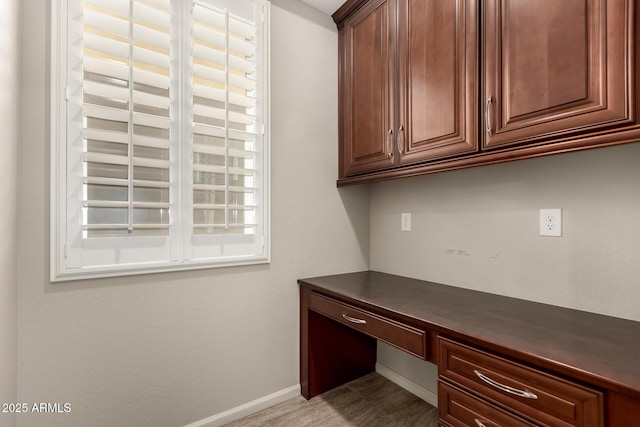 unfurnished office featuring baseboards and built in desk