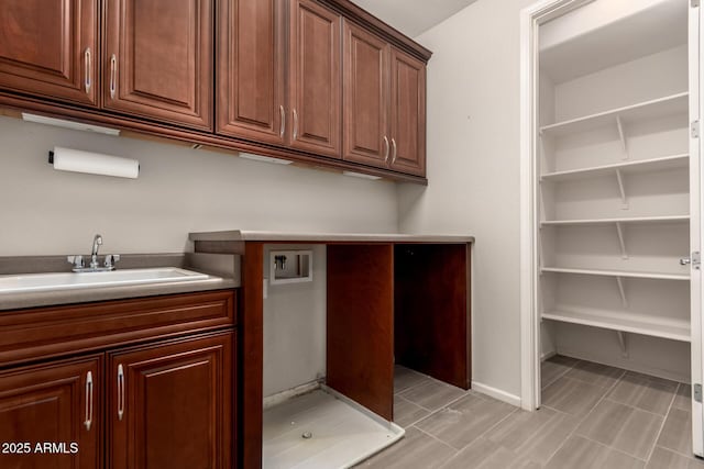 laundry area with a sink, baseboards, hookup for a washing machine, and cabinet space