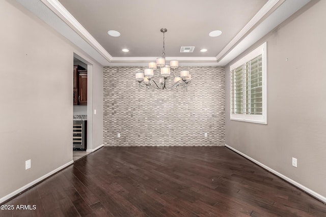unfurnished dining area featuring visible vents, wood finished floors, beverage cooler, an inviting chandelier, and a tray ceiling