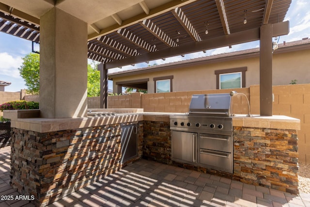 view of patio featuring exterior kitchen, a pergola, and fence