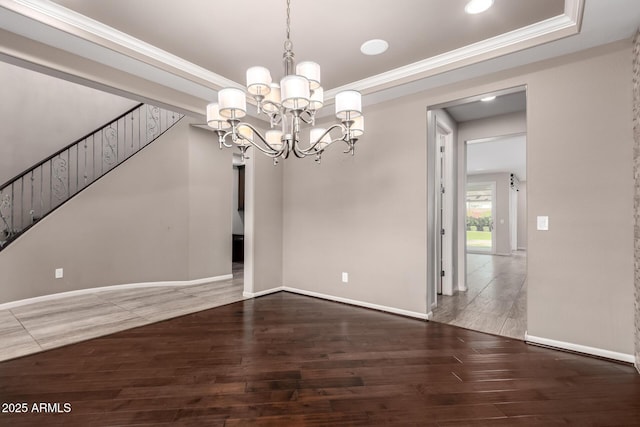 unfurnished dining area featuring crown molding, a tray ceiling, a chandelier, and hardwood / wood-style flooring