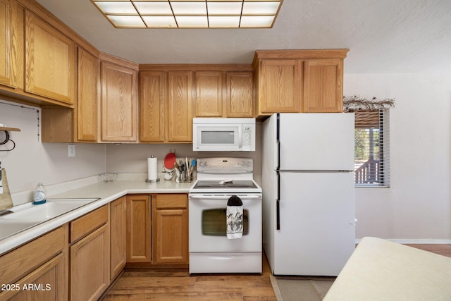 kitchen featuring light wood-type flooring, white appliances, and light countertops