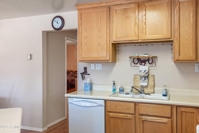 kitchen featuring a sink, light countertops, baseboards, and white dishwasher