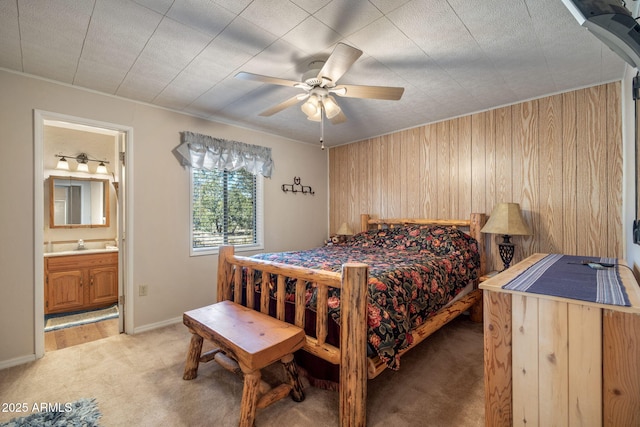 bedroom with baseboards, light carpet, ensuite bathroom, a ceiling fan, and a sink